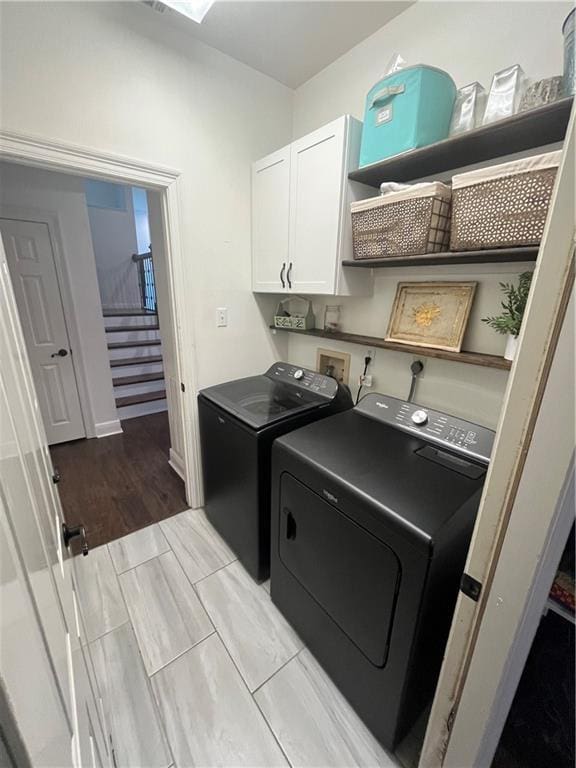 clothes washing area with washer and clothes dryer and cabinets