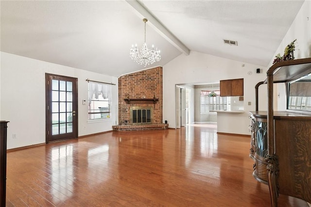 unfurnished living room with a fireplace, vaulted ceiling with beams, hardwood / wood-style flooring, and an inviting chandelier