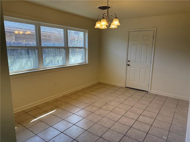 empty room with a notable chandelier and light tile patterned floors