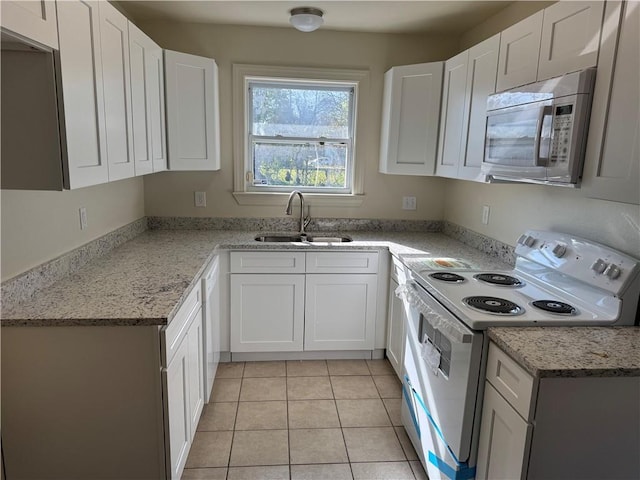 kitchen with white cabinetry, light tile patterned flooring, white appliances, and sink