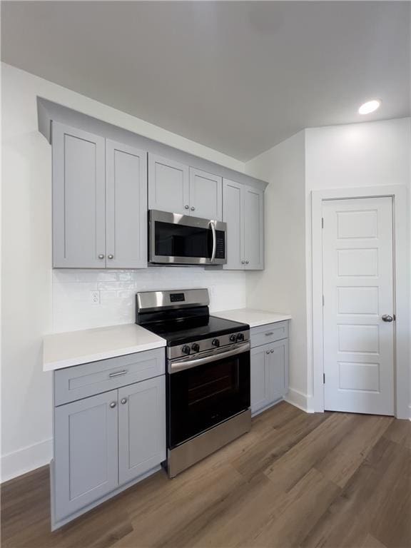 kitchen with gray cabinets, appliances with stainless steel finishes, and dark hardwood / wood-style floors