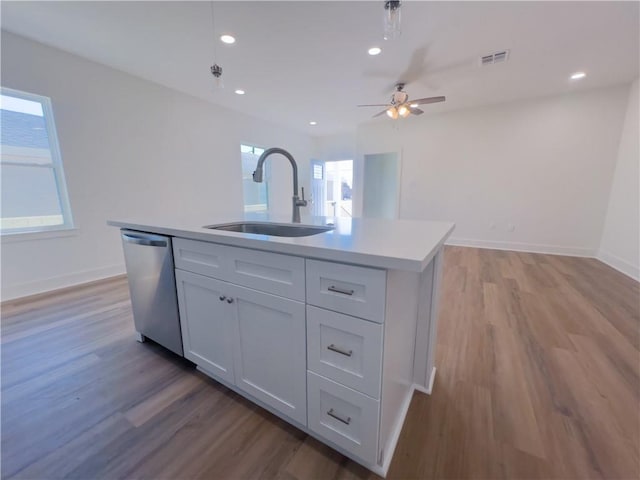 kitchen featuring wood-type flooring, sink, white cabinets, a kitchen island with sink, and stainless steel dishwasher