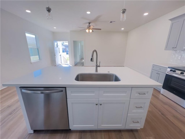 kitchen featuring sink, hanging light fixtures, a kitchen island with sink, stainless steel appliances, and light hardwood / wood-style flooring