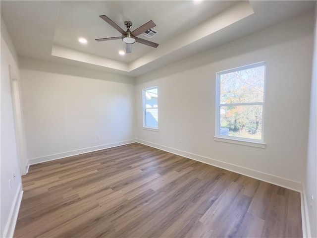 spare room with hardwood / wood-style flooring, ceiling fan, and a tray ceiling