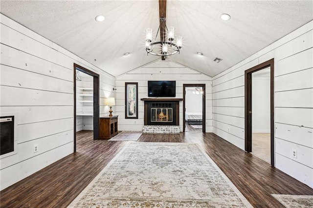 unfurnished living room featuring a textured ceiling, dark hardwood / wood-style floors, lofted ceiling, and a notable chandelier