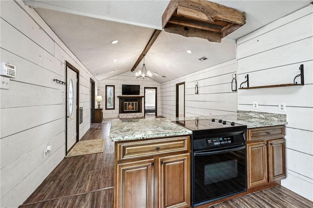 kitchen with wood walls, dark wood-type flooring, a brick fireplace, black electric range, and vaulted ceiling with beams