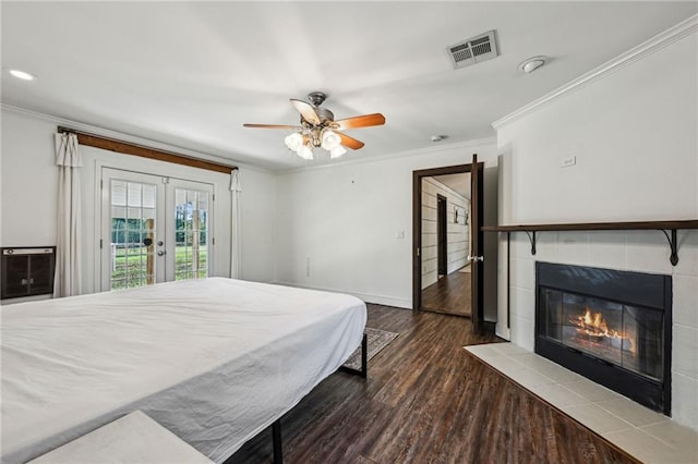 bedroom featuring access to exterior, ceiling fan, french doors, a tiled fireplace, and ornamental molding