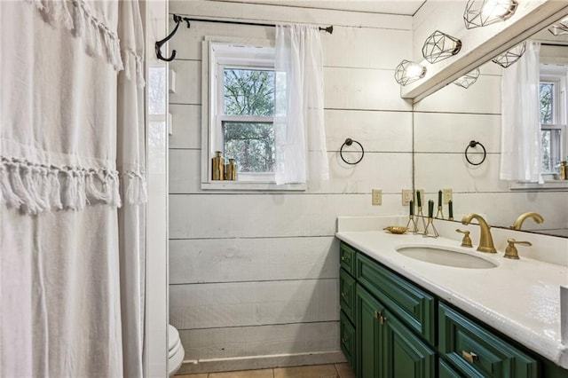 bathroom with tile patterned floors, vanity, toilet, and a wealth of natural light