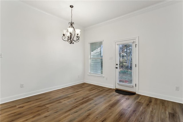 empty room featuring dark hardwood / wood-style flooring, a notable chandelier, and ornamental molding