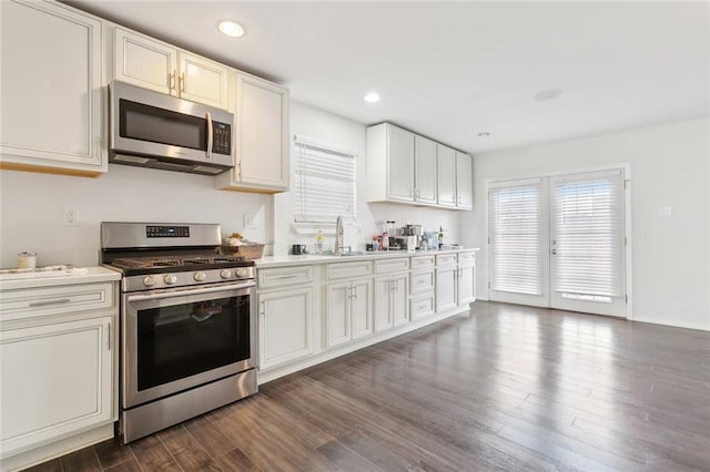 kitchen featuring stainless steel appliances, white cabinetry, dark wood-type flooring, and sink