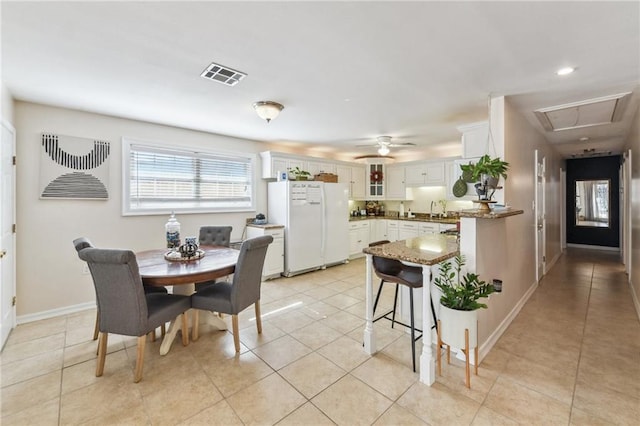 tiled dining room with ceiling fan and sink