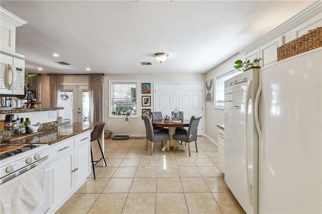 kitchen featuring french doors, white appliances, light tile patterned floors, dark stone countertops, and white cabinets