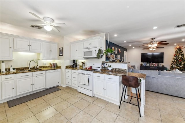 kitchen featuring white cabinetry, white appliances, kitchen peninsula, and dark stone counters