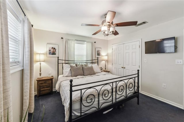 bedroom with dark colored carpet, ceiling fan, and a closet