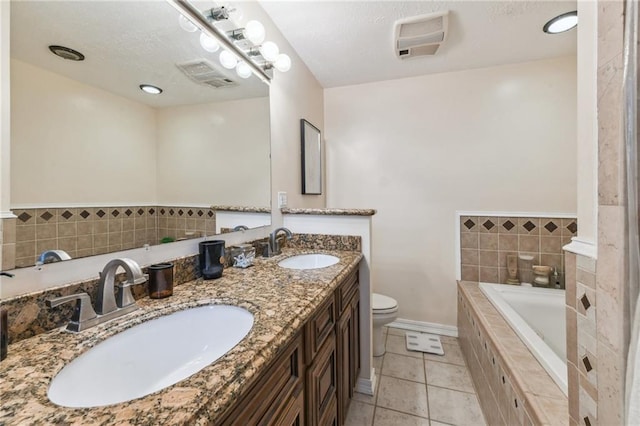 bathroom featuring tiled tub, tile patterned flooring, vanity, and toilet