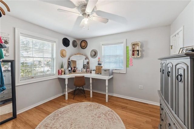 office space with ceiling fan, built in desk, and light wood-type flooring