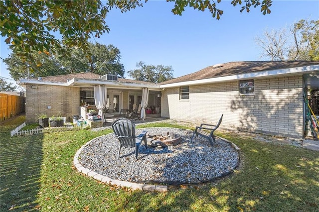 rear view of property with a lawn, a patio area, and an outdoor fire pit