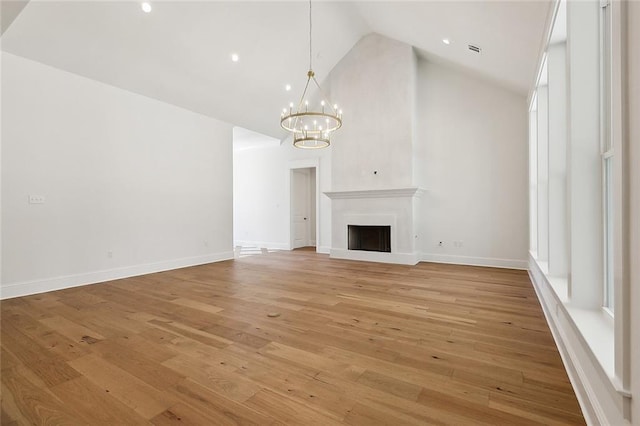 unfurnished living room with light hardwood / wood-style flooring, high vaulted ceiling, and a chandelier