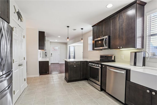 kitchen with kitchen peninsula, light tile patterned flooring, pendant lighting, and appliances with stainless steel finishes