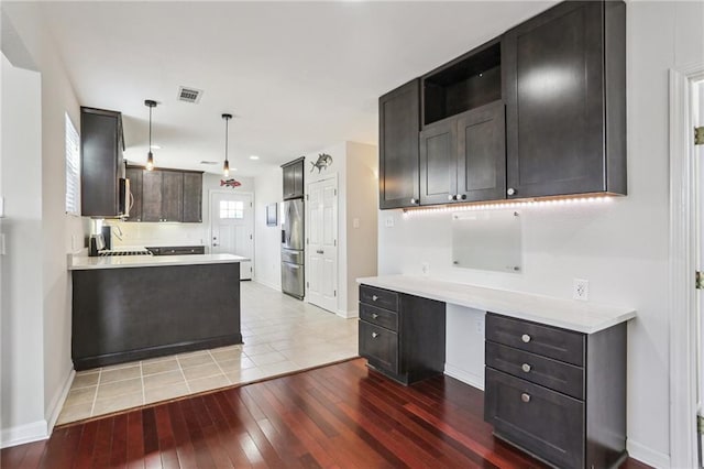 kitchen with stainless steel fridge, dark brown cabinetry, light hardwood / wood-style flooring, and hanging light fixtures