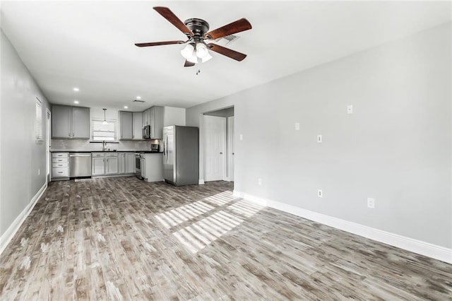 unfurnished living room with ceiling fan, sink, and light hardwood / wood-style floors