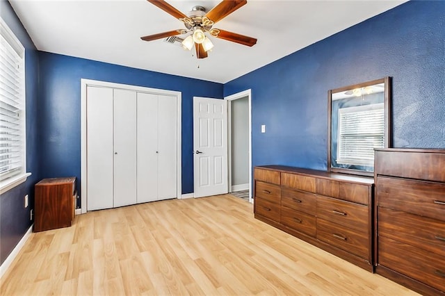 unfurnished bedroom with ceiling fan, a closet, multiple windows, and light hardwood / wood-style flooring