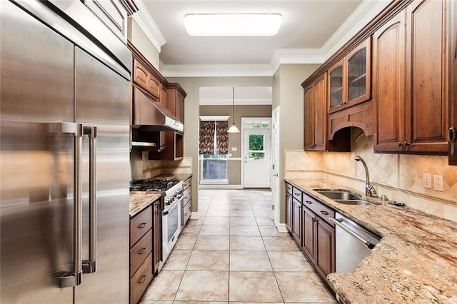 kitchen with premium appliances, light stone counters, light tile patterned floors, and sink