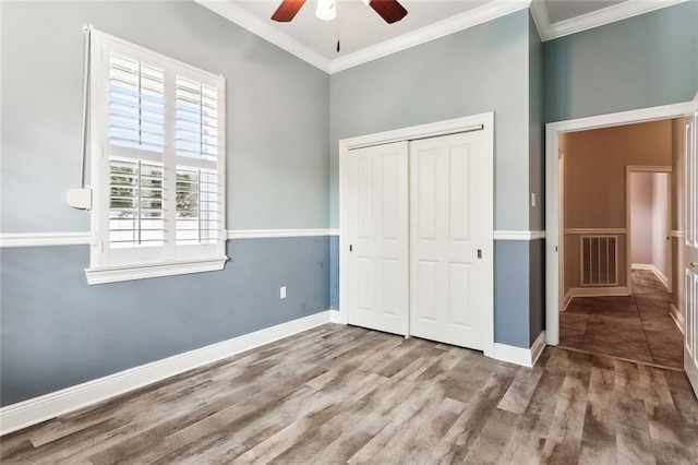 unfurnished bedroom with a closet, ceiling fan, crown molding, and hardwood / wood-style flooring