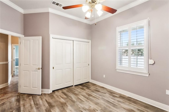 unfurnished bedroom featuring ceiling fan, light hardwood / wood-style flooring, crown molding, and a closet