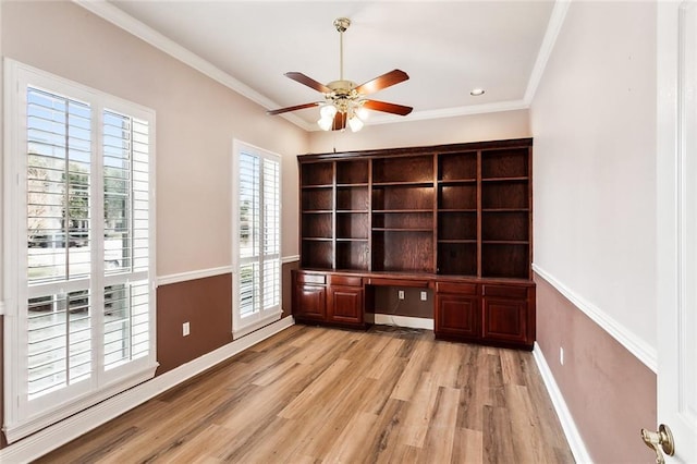 unfurnished office featuring ceiling fan, light hardwood / wood-style flooring, built in desk, and ornamental molding