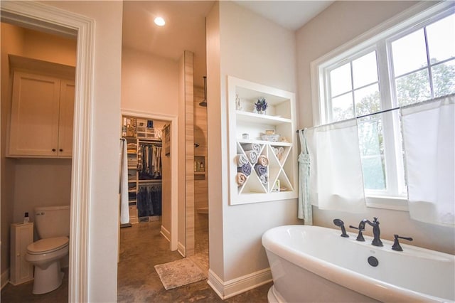 bathroom featuring built in shelves, a bath, and toilet