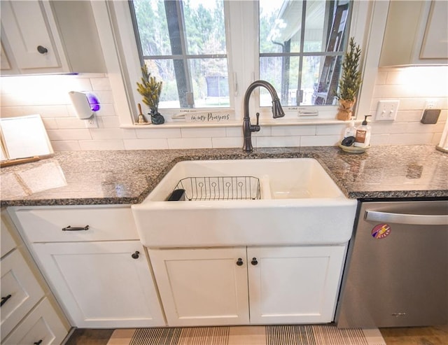 kitchen with white cabinetry, sink, stainless steel dishwasher, dark stone countertops, and decorative backsplash