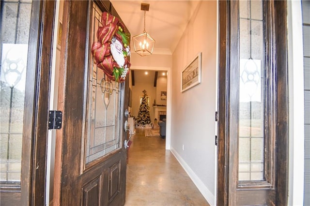 entryway with crown molding, concrete floors, and a notable chandelier