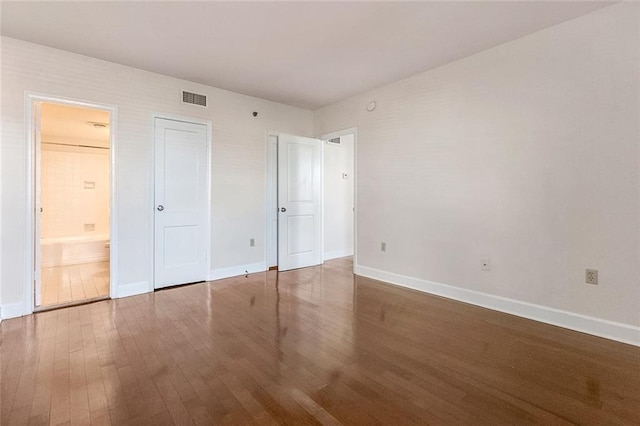 unfurnished bedroom featuring baseboards, visible vents, and wood finished floors