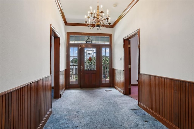 carpeted entrance foyer with a chandelier and ornamental molding