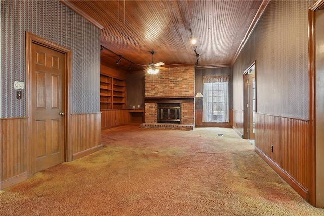 unfurnished living room with ceiling fan, rail lighting, light colored carpet, a fireplace, and wood ceiling