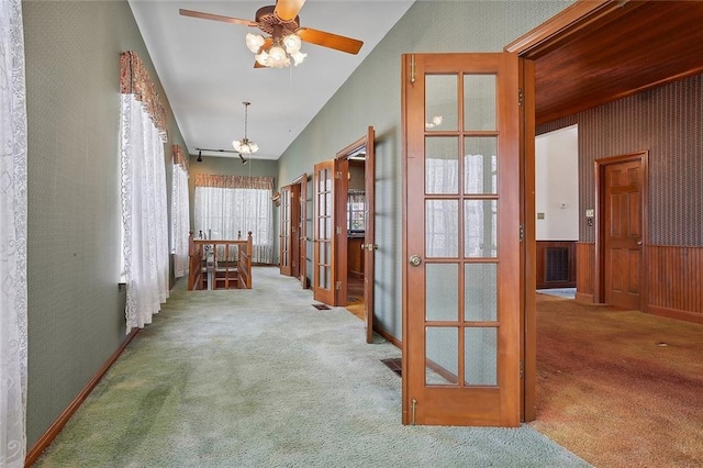 hallway with carpet, french doors, an inviting chandelier, lofted ceiling, and wood walls