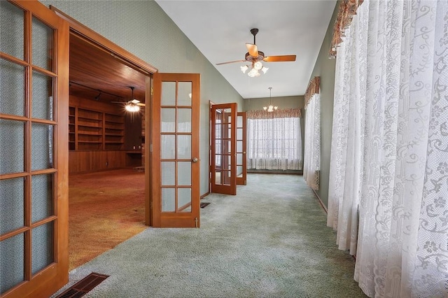 hallway featuring carpet flooring, an inviting chandelier, vaulted ceiling, and french doors