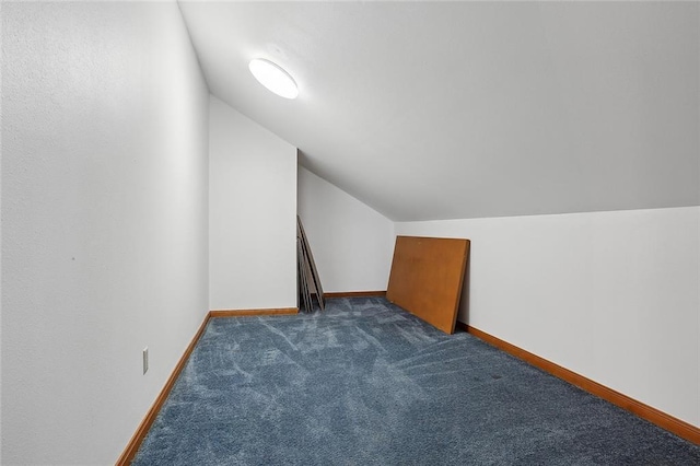 additional living space with dark colored carpet and lofted ceiling