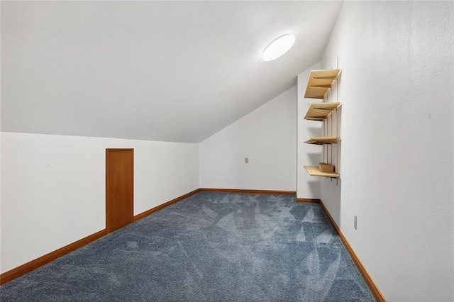 additional living space with dark colored carpet and vaulted ceiling