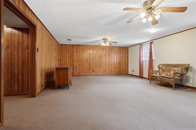 living area with light colored carpet, crown molding, and wood walls