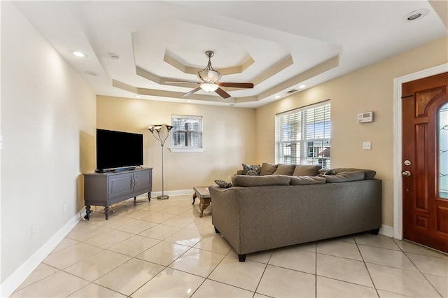 living room featuring light tile patterned floors, a raised ceiling, and ceiling fan