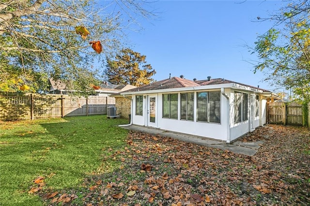 rear view of house featuring a sunroom, a yard, and central AC