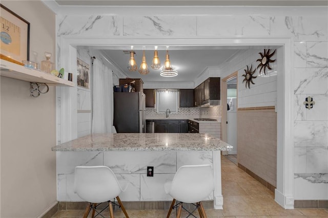 kitchen with a kitchen breakfast bar, stainless steel fridge, dark brown cabinetry, and kitchen peninsula