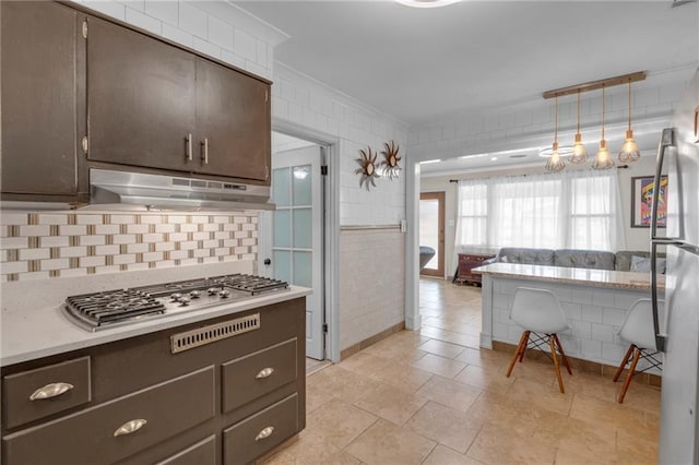 kitchen featuring tasteful backsplash, dark brown cabinetry, stainless steel appliances, crown molding, and pendant lighting