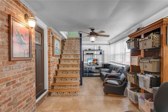 living room featuring ceiling fan, ornamental molding, and brick wall