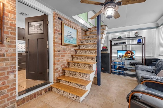 interior space featuring ceiling fan, crown molding, and brick wall