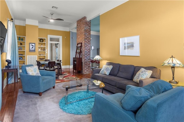 living room with decorative columns, wood-type flooring, built in features, and ceiling fan