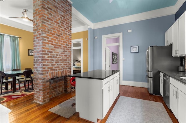 kitchen with white cabinetry, a brick fireplace, wood-type flooring, and a kitchen island