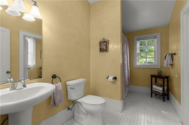 bathroom with an inviting chandelier, sink, toilet, and tile patterned flooring